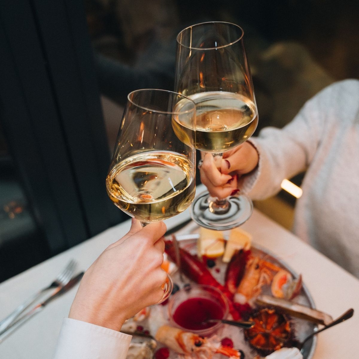 Due persone brindano con calici di vino bianco a tavola da Il Cestino Milano