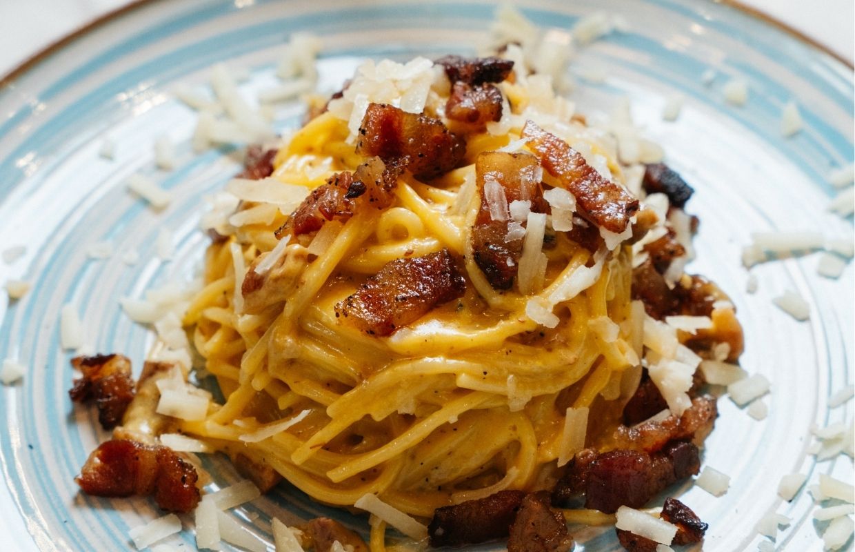 Piatto di spaghetti alla carbonara con guanciale croccante e crema d'uovo finale